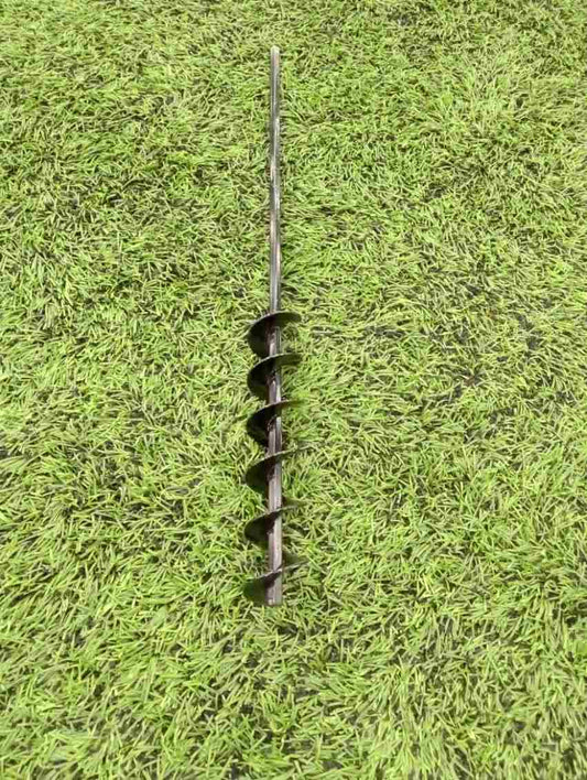 A steel SMART Base Auger designed for cleaning base anchors on a grassy surface.