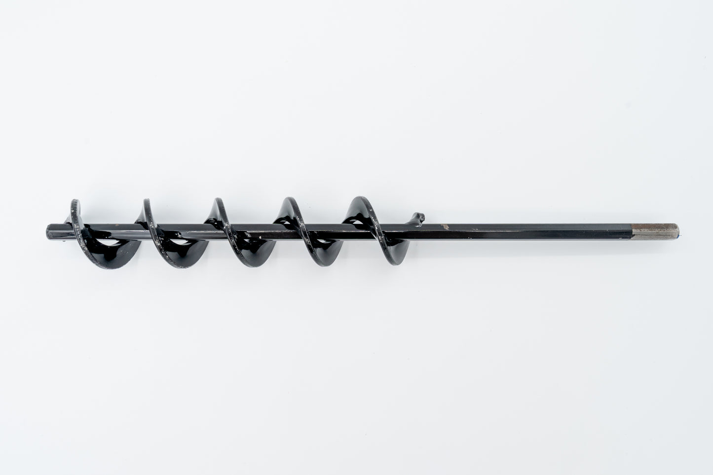 A steel SMART Base Auger designed for cleaning base anchors on a grassy surface.