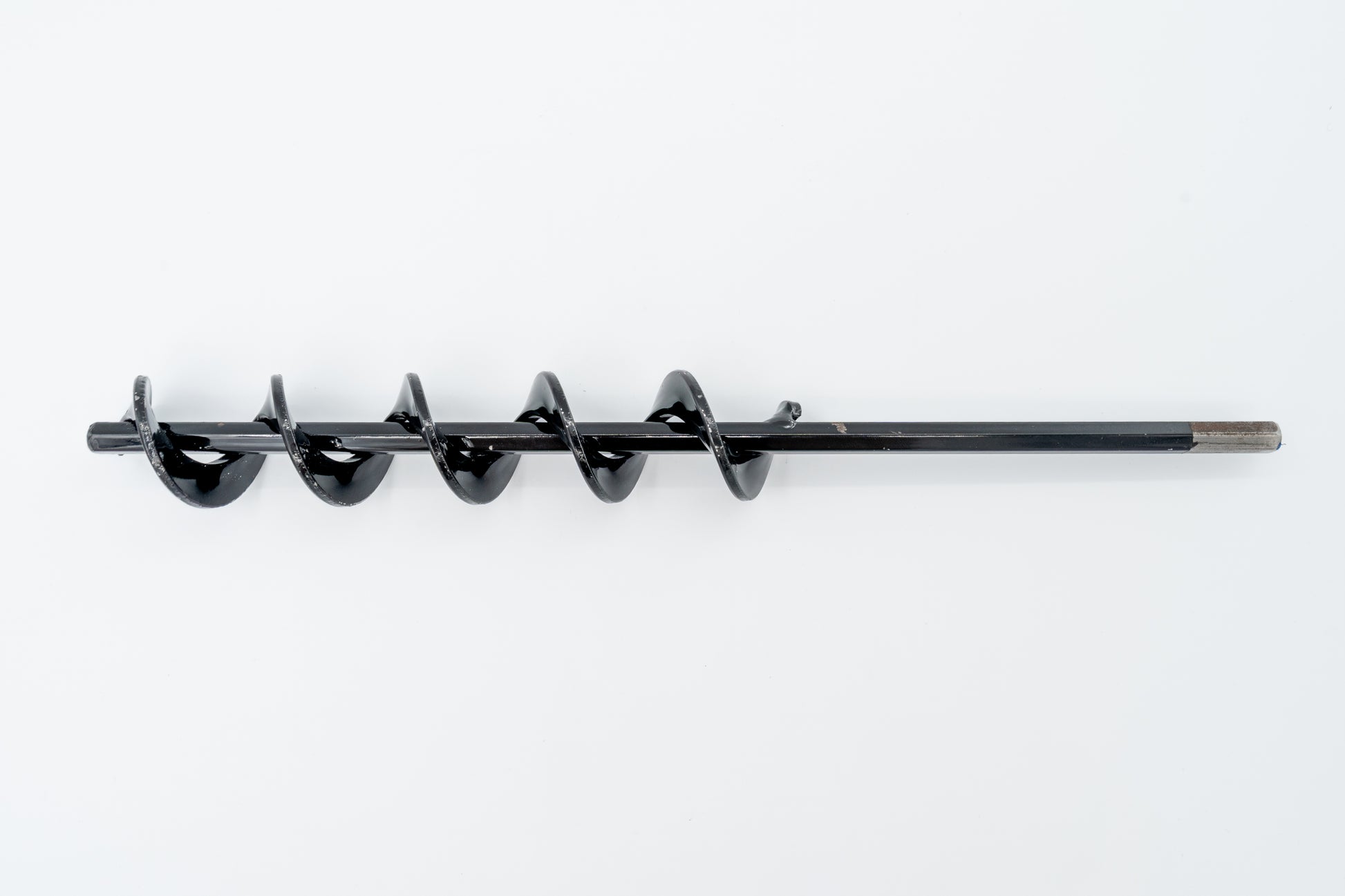 A steel SMART Base Auger designed for cleaning base anchors on a grassy surface.