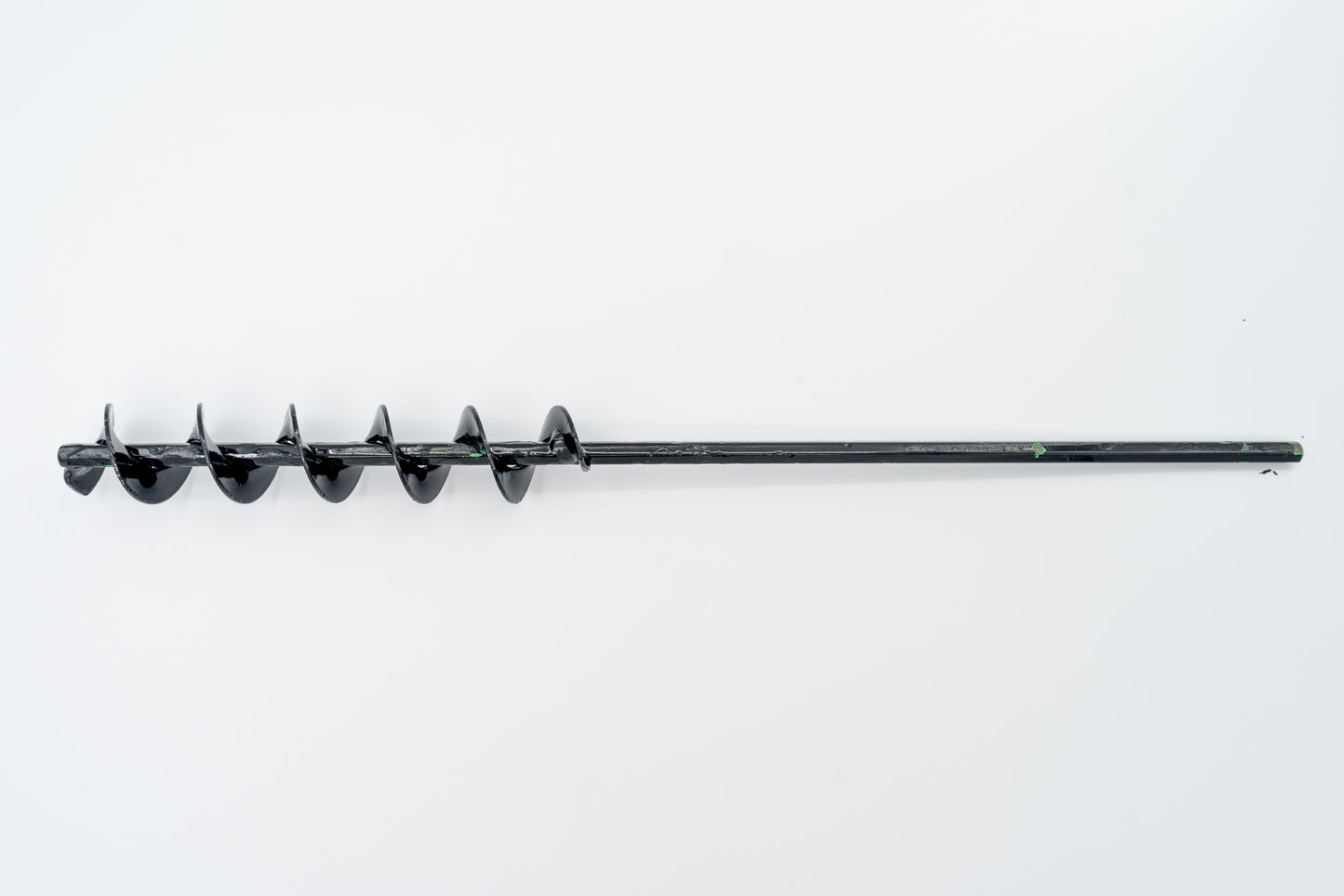 A steel SMART Base Auger designed for cleaning base anchors on a grassy surface.